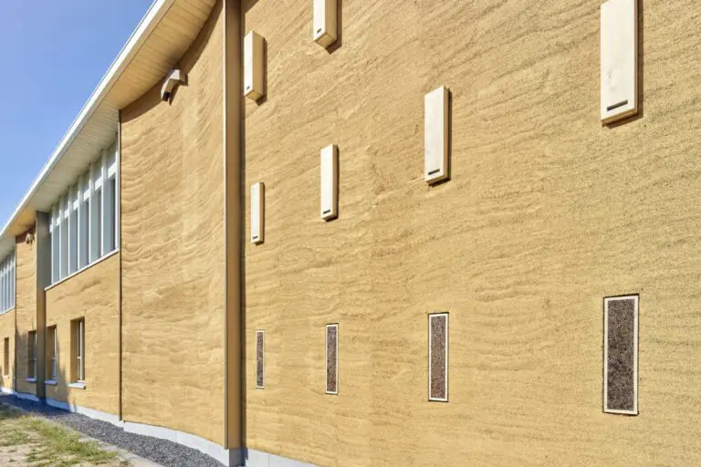 Biodiversiteit aan de gevel van het gemeentehuis: nestkasten voor vleermuizen, zwaluwen en bijen. De kleurverschillen in de kalkhennepgevel horen bij het natuurproduct.