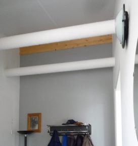 De kanalen voor de aanvoer van voorverwarmde verse lucht naar de woonkamer lopen in het zicht onder het schuine plafond in de hal.